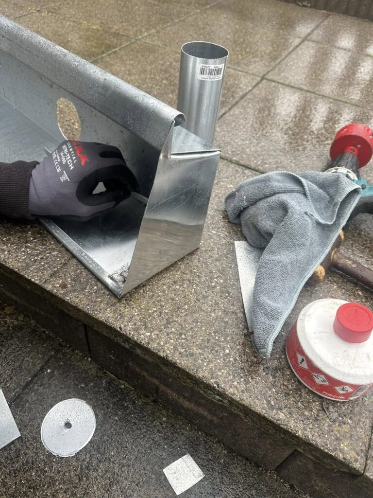 Close-up van nieuw zinken hoekstuk en regenpijp in Leyenburg